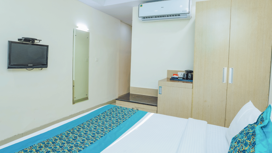 A compact hotel room featuring a double bed with a blue and white runner, and a mirror - Hyphen Grand, Haridwar