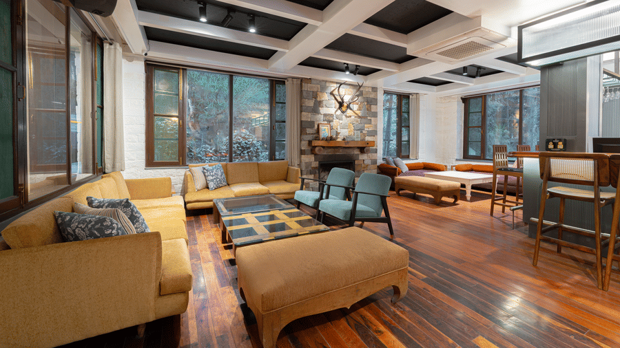 A sophisticated lounge featuring a long bar with high stools, polished wooden floors, and a coffered ceiling - Johnson Lodge & Spa, Manali