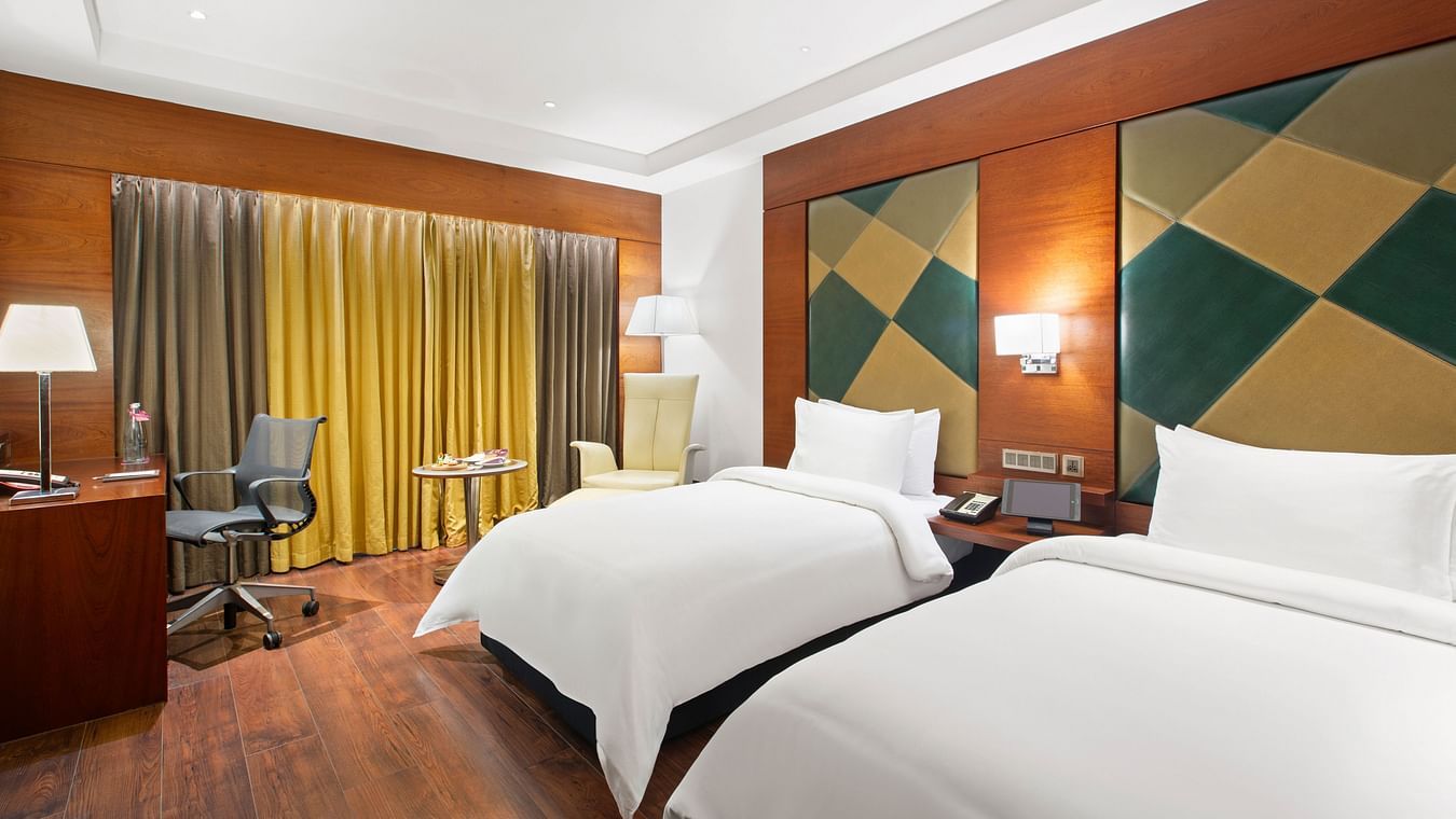 Executive Room with two cozy beds and a corner seating area at The Residency Towers Coimbatore