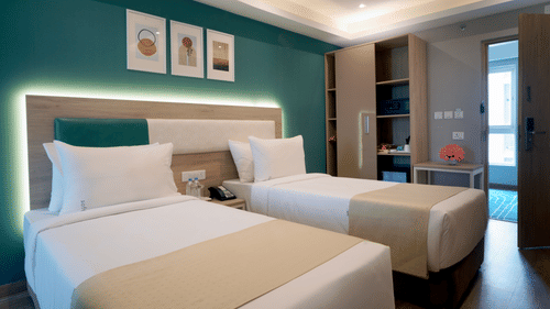 twin beds, artwork on the wall, a wardrobe with an in-room safe, snacks, and a minibar inside one of the executive rooms at Sarovar Portico, Kolkata Rajarhat