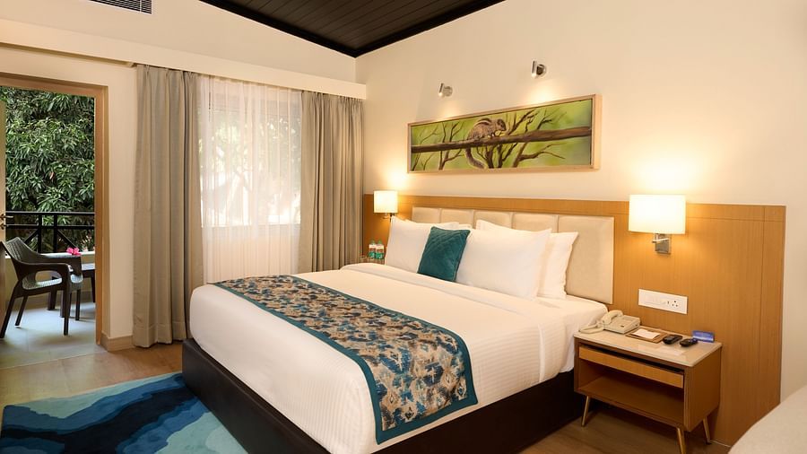 view of a double bed and night stand in the Cottage at ABN Sarovar Portico, Jim Corbett