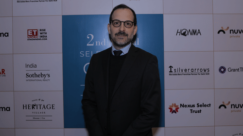 A man standing with a smile, positioned behind a promotional board. - Heritage Village Resorts & Spa