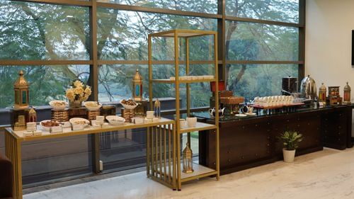 A buffet spread arranged by the window, featuring bowls of delights and elegant decor. - Heritage Village Resorts & Spa