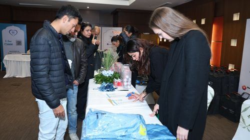 An group of a people looking at the table where several items are placed including some sheets, documents, packed suites, bouquets, etc. at Heritage Village Resorts & Spa