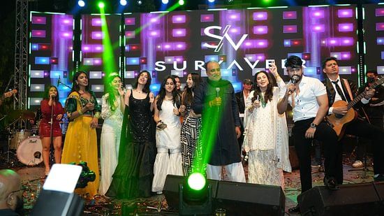 Performers on stage celebrating during a vibrant musical event under colourful lighting.