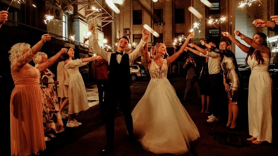 A couple in western wedding attire enjoying the after party celebrations with fireworks.