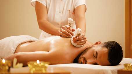 Woman using herbal pouches to massage a man's back.