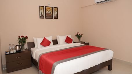 A bedroom at Nazri The Verda Hotel, Arambol, featuring a bed with cushions, bedside tables, and wall decorations.