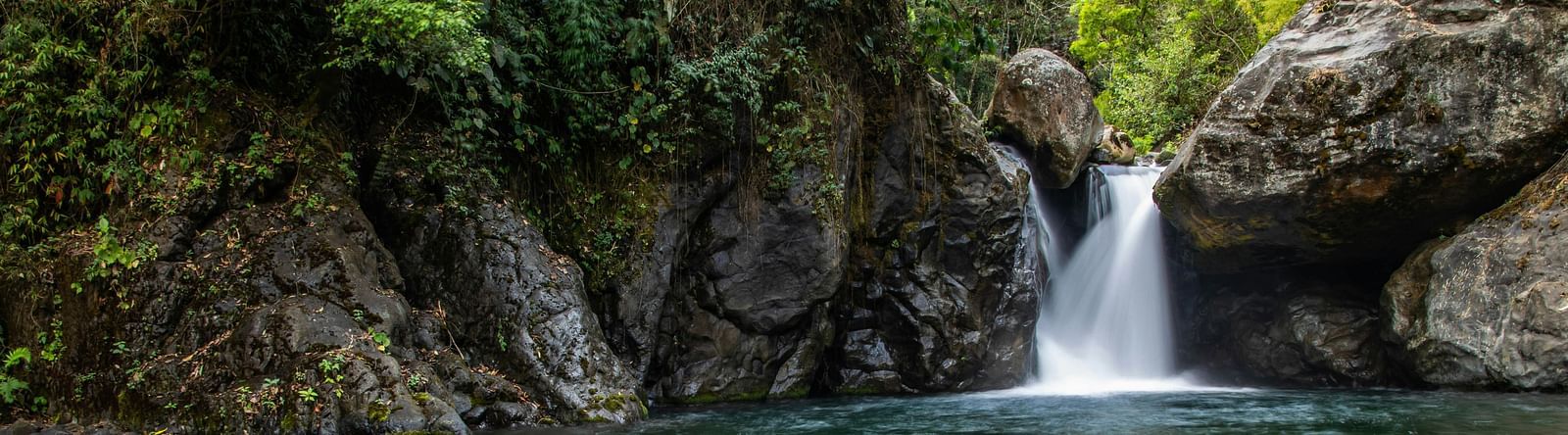 View of Corbett waterfall with rocks and surrounded by trees.