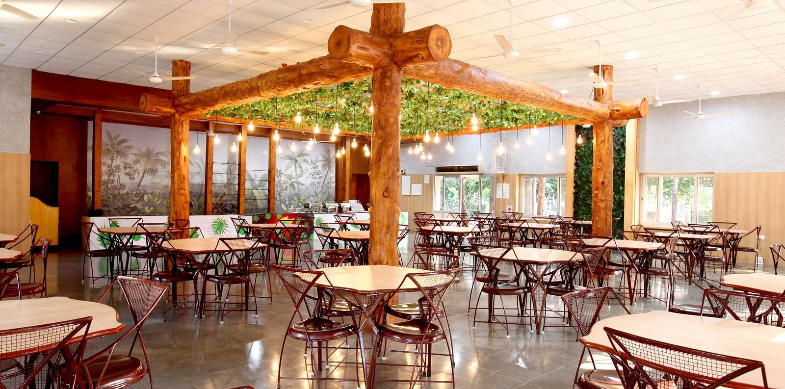 An elaborate seating arrangement at Greens Inn Restaurant featuring wooden furnishing and lit bulbs hanging from the ceiling at Greens Inn - Cozy Dining in Hyderabad.