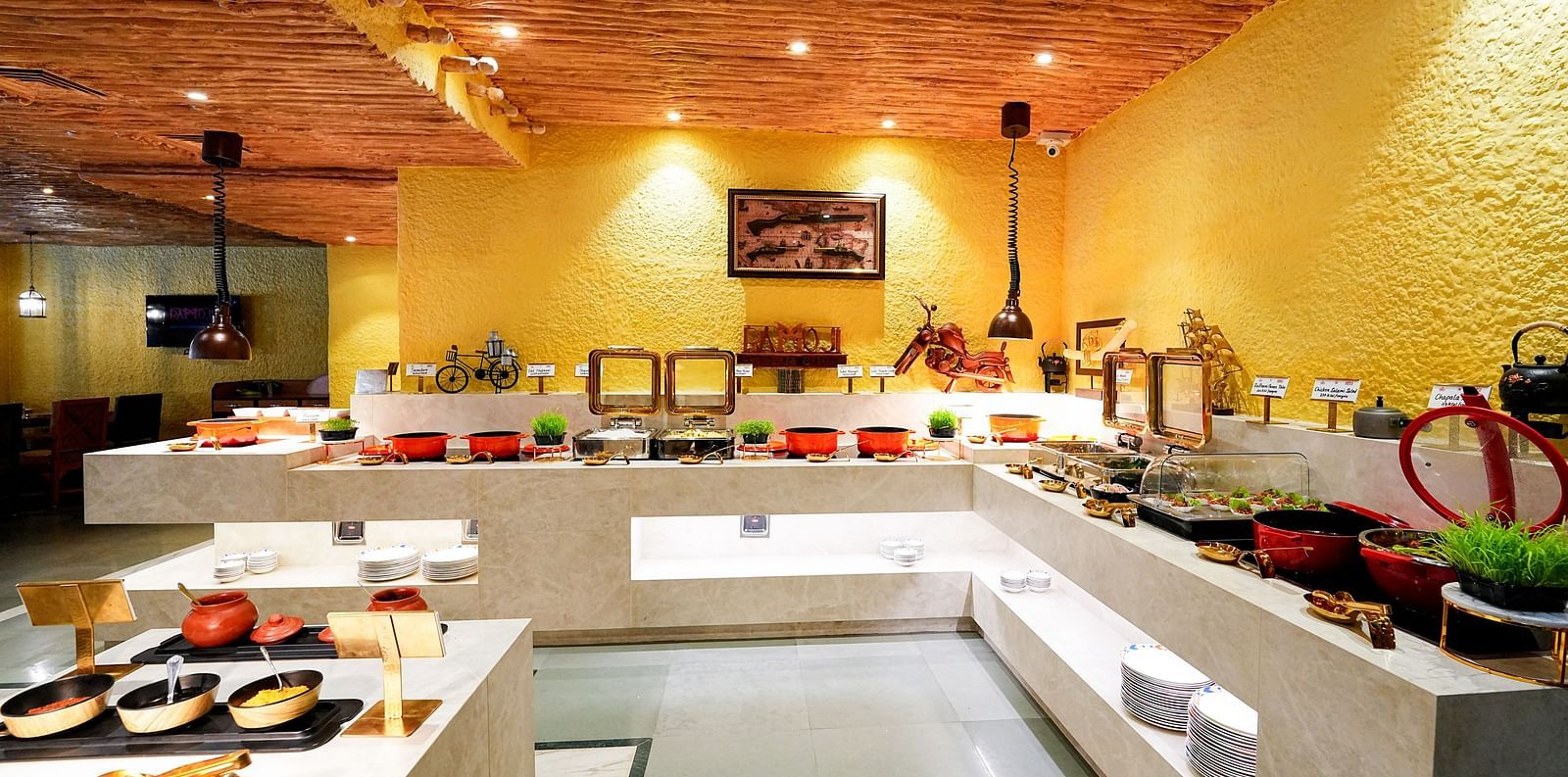 A comprehensive view of a buffet setup in a room with a rustic ceiling and yellow walls. - Tara, Comfort Hotel in Hyderabad - Ramoji Film City.