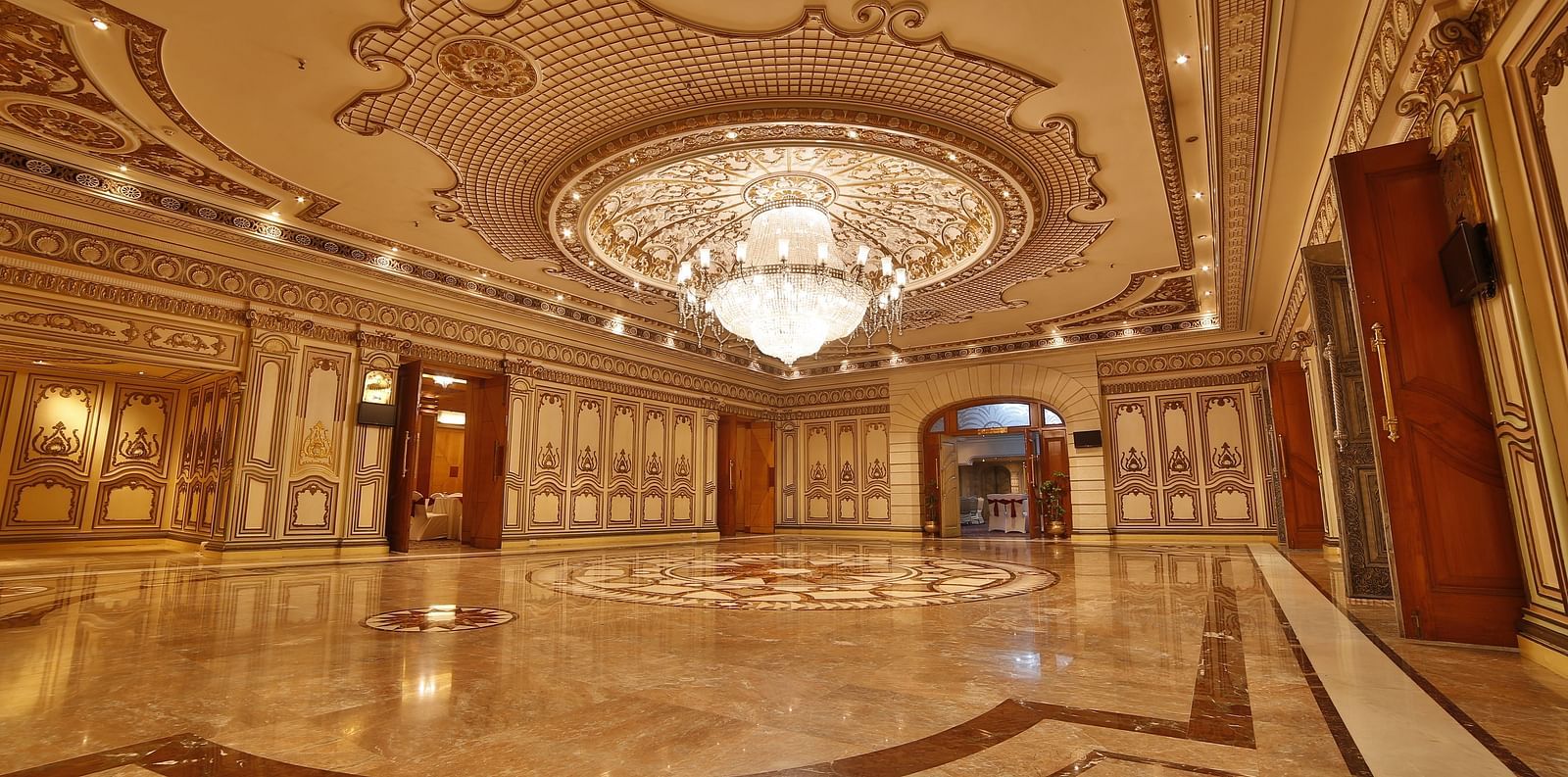 Interiors of Rang Mahal hall A grand hotel suite with an opulent red and white decor, large bed, and seating area, reflecting a traditional style at Sitara Luxury Hotel in Hyderabad near Ramoji Film City.