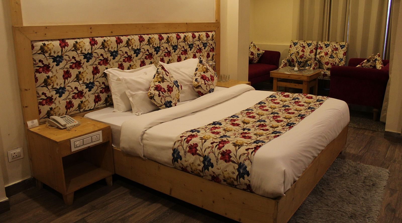 A well-furnished bedroom with floral headboards, warm lighting, and comfortable bedding at Dagshai Manor Kasauli - Inde Hotels.