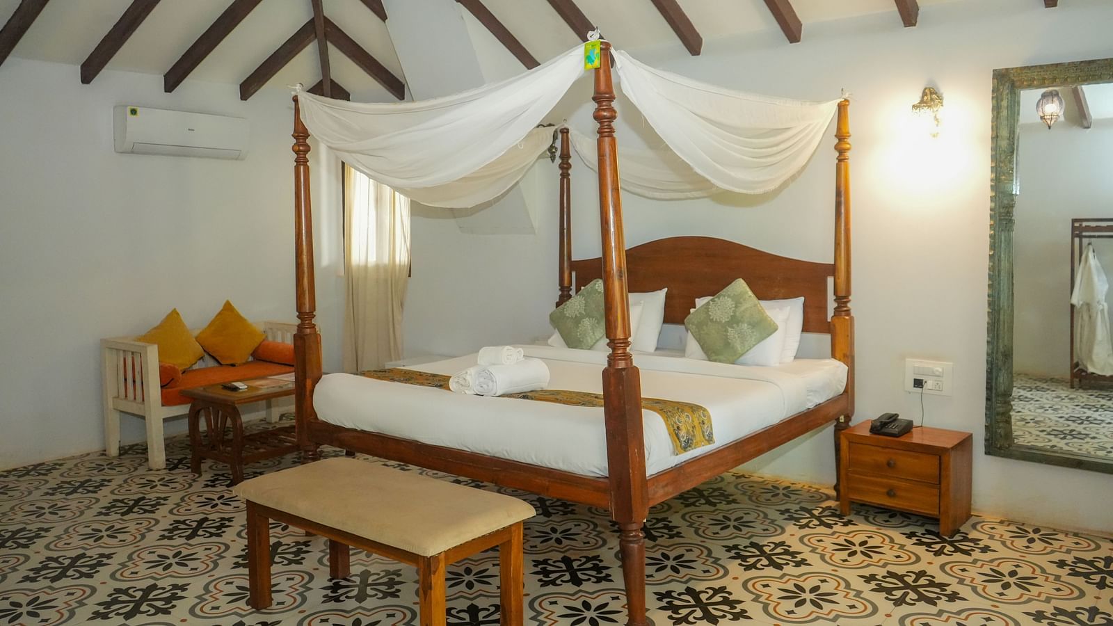 Bright room featuring a wooden four-poster bed with yellow cushions and detailed tiled flooring at De Soul Santé, Morjim.