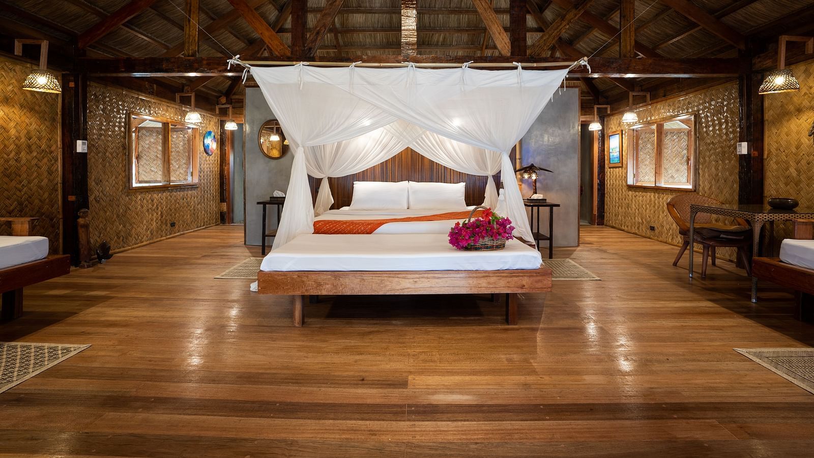 View of a wooden bedroom at Flower Island Resort with a white canopy bed and nightstands on both sides.