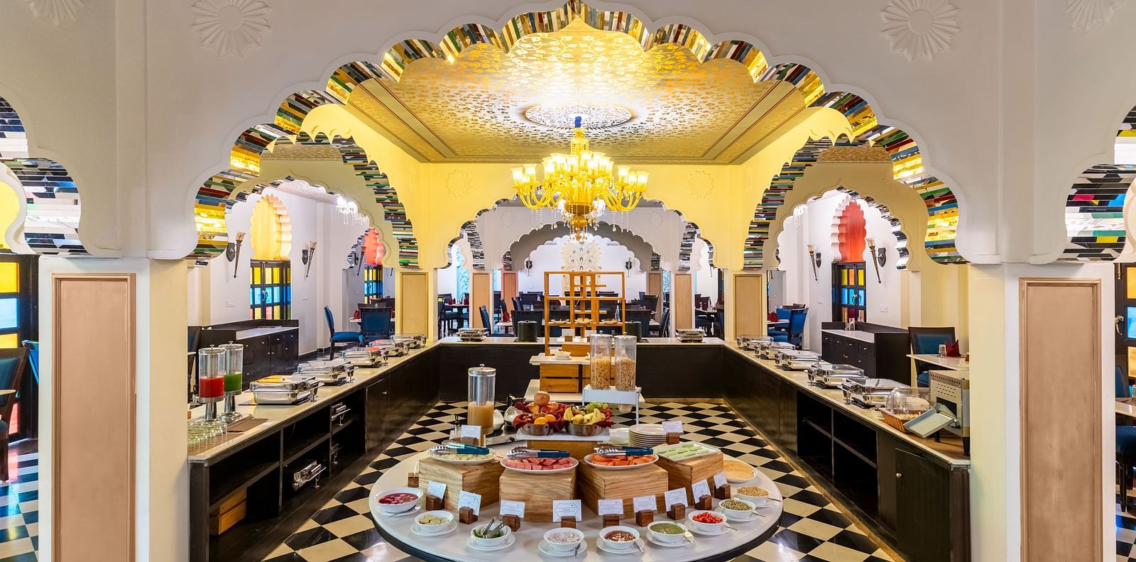 Lavish buffet dining area with black-and-white flooring and chandeliers at Kesar Bagh Palace.