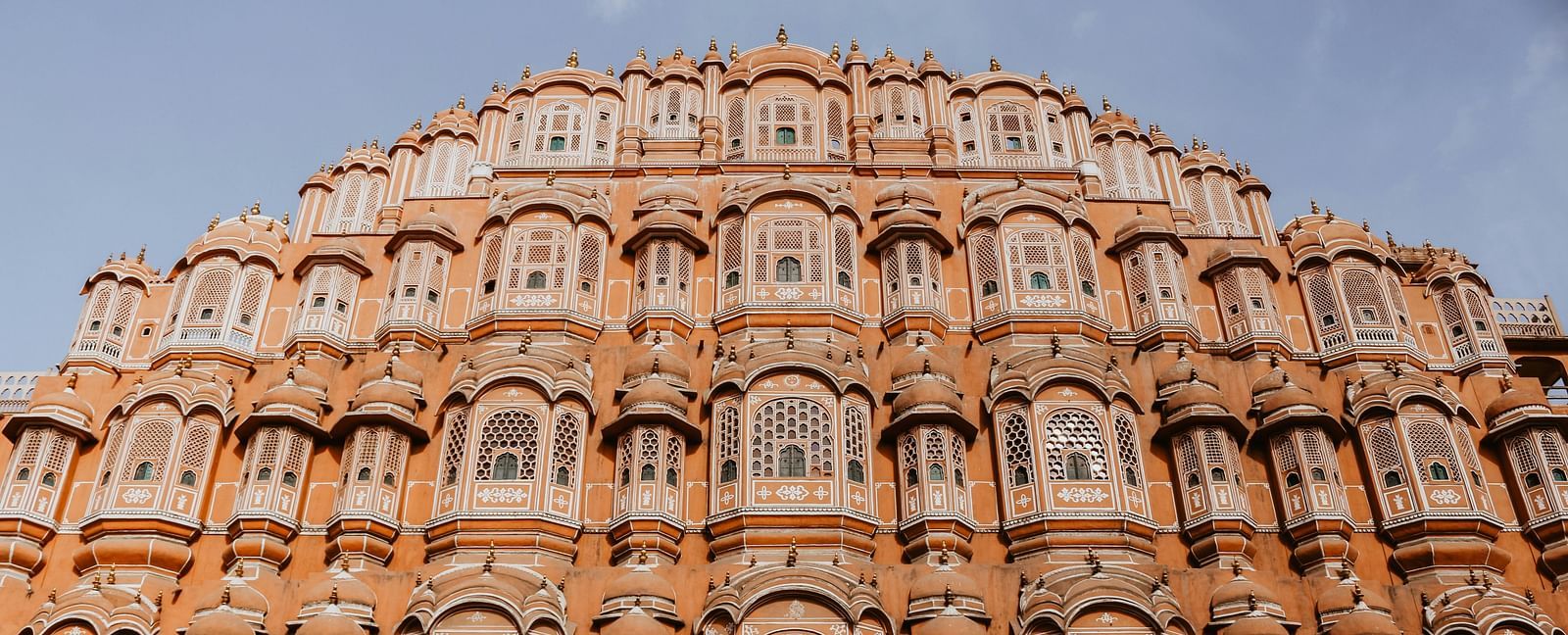 An impressive view of the Hawa Mahal, a pink sandstone palace in Jaipur, India, with numerous intricate windows