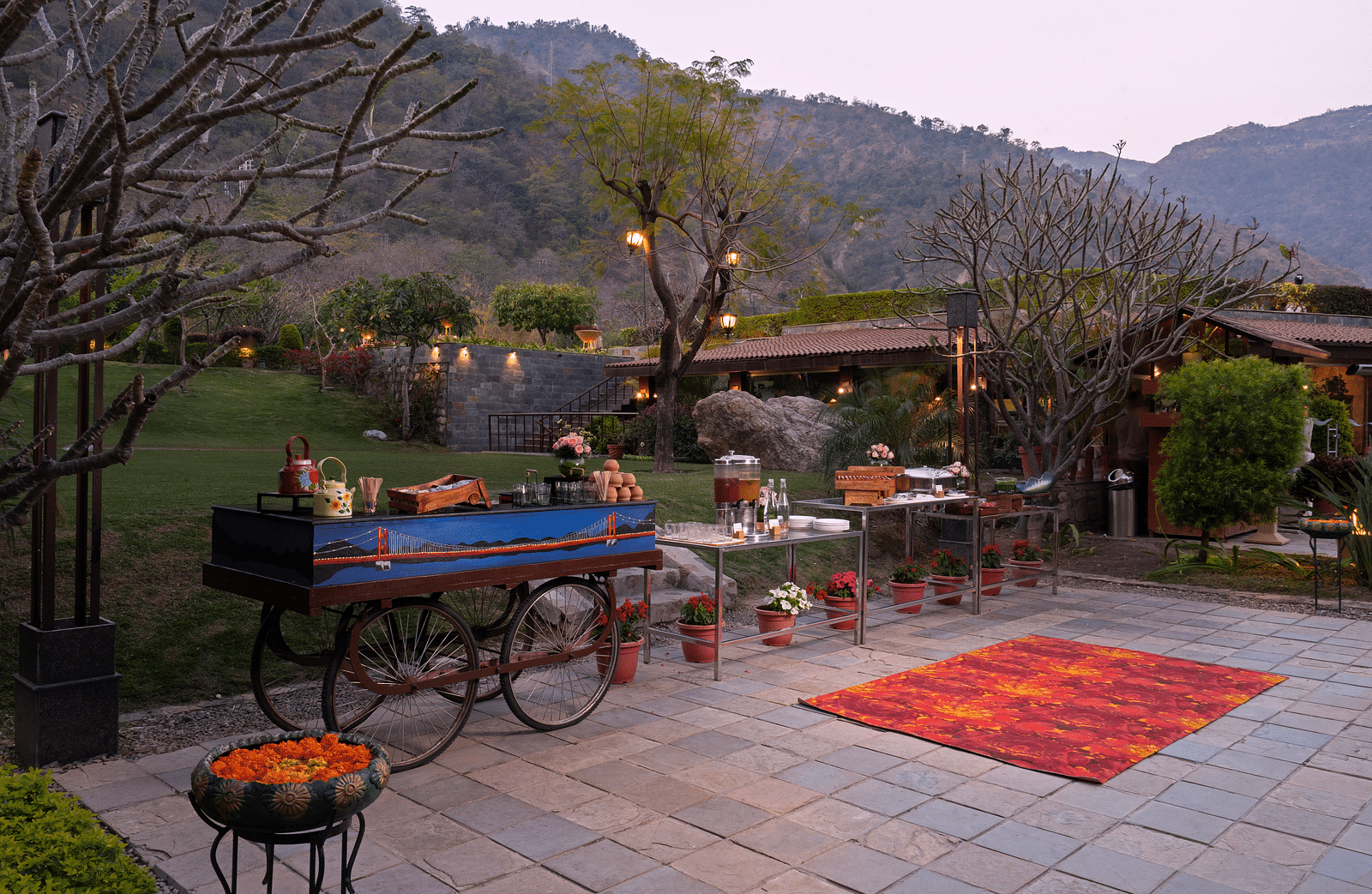 Food at outdoor food stations. There are mountains in the background and lush surrounding the scene.