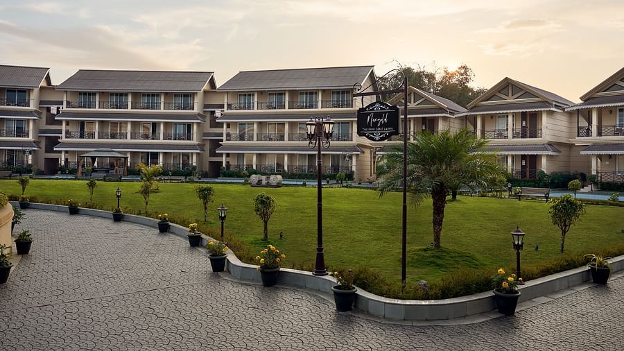 Wide-angle view of a well-maintained lawn surrounded by elegant multi-storey resort buildings at sunset - Voyage The Solitaire Bliss.