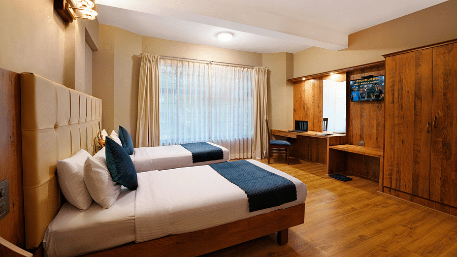 An elegant room featuring twin beds and wooden furnishings - Cross Roads Inn, Bengaluru