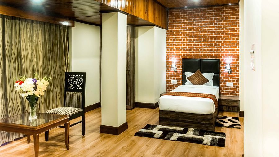 An image of a suite at the Ecotel Tin Tin, Bijanbari featuring a single bed, bed side tables, a table and a chair and other amenities