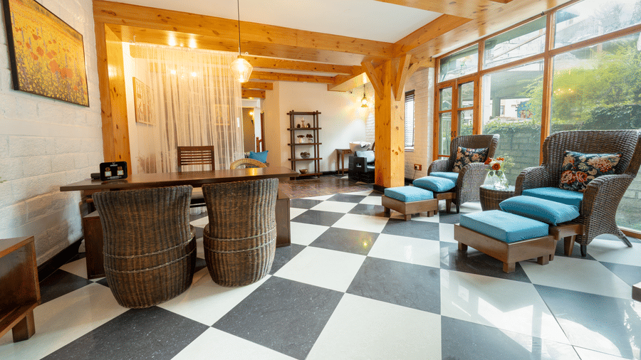 A sophisticated lounge and reception area with black and white checker board flooring and blue wicker chairs - Johnson Lodge & Spa, Manali