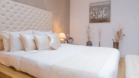 Side view of the bedroom of the Suite at The Prachi Hotel, Bhubaneswar, showcasing its plush king size bed with an upholstered headboard placed in a room with minimal Bohemian interiors.