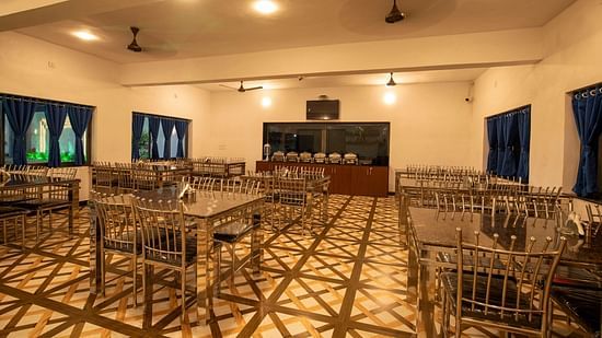A restaurant with dining tables and chairs arranged with bright lighting and blue curtains - VITS Select Diamond Resort, Sasan Gir