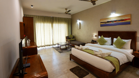 Superior room with a large bed, 2 fans, green shades, a TV, and wooden cabinets at Hotel Sonar Bangla, Taki.