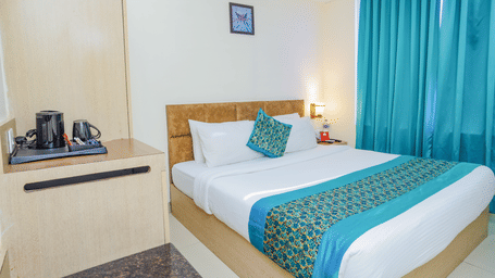 A hotel room with a double bed, a vibrant blue bed runner, and a wooden headboard - Hyphen Grand, Haridwar