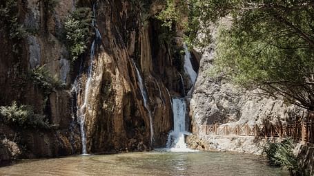 A view of waterfall passing by a rocky surface  on a sunny day.