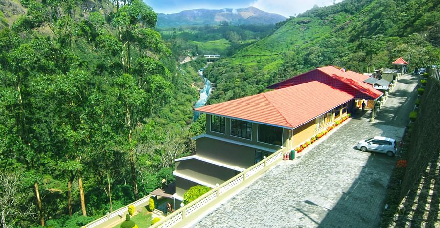 Abad Copper Castle Resort nestled in a valley with lush green hills.