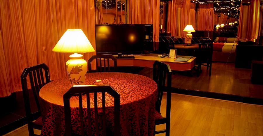 alt-text  Hotel Yasodha Towers - Interior view of a room containing a table lit with a lamp and mirror placed in the background