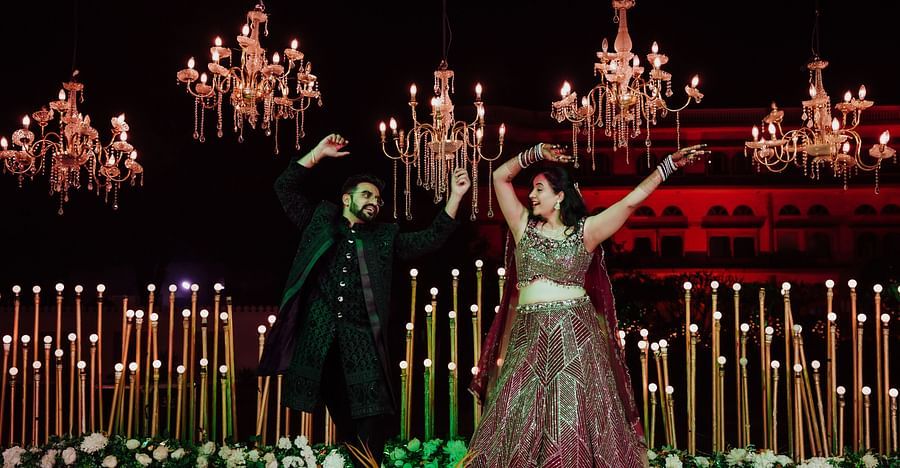 Bride and groom performing a dramatic dance pose on a stage decorated with chandeliers and candles.
