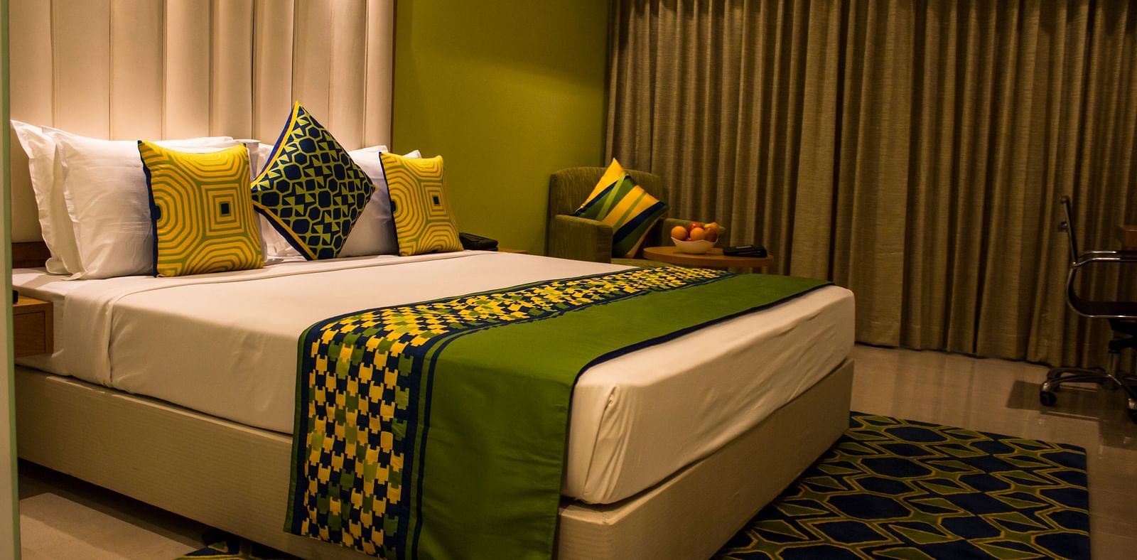 Side view a room with a bed and  pillows arranged on it  along with  a side table | Regency Tirunelveli By GRT Hotels