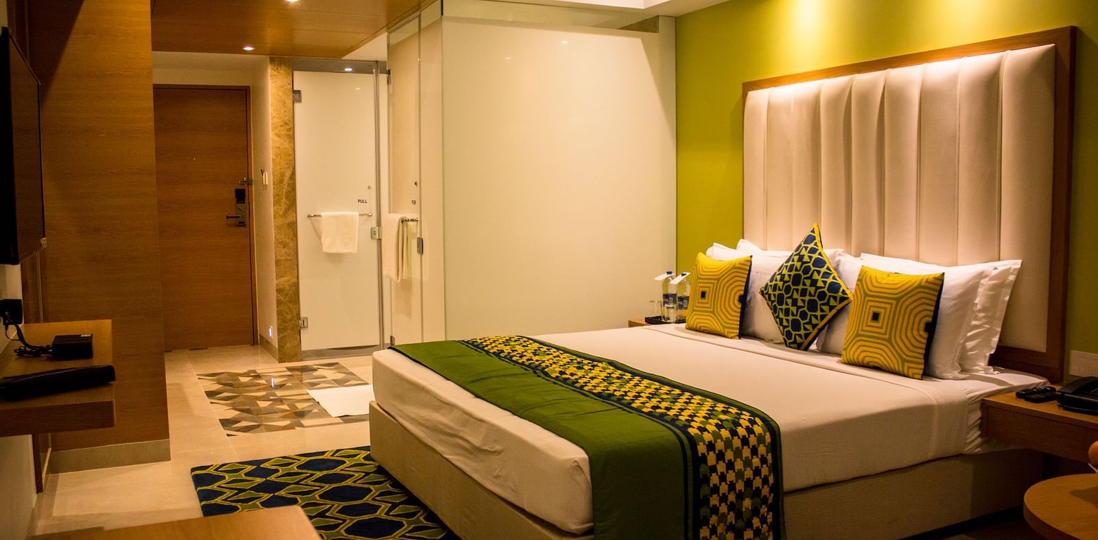 A room with a bed and  pillows arranged on it  along with  a side table | Regency Tirunelveli By GRT Hotels