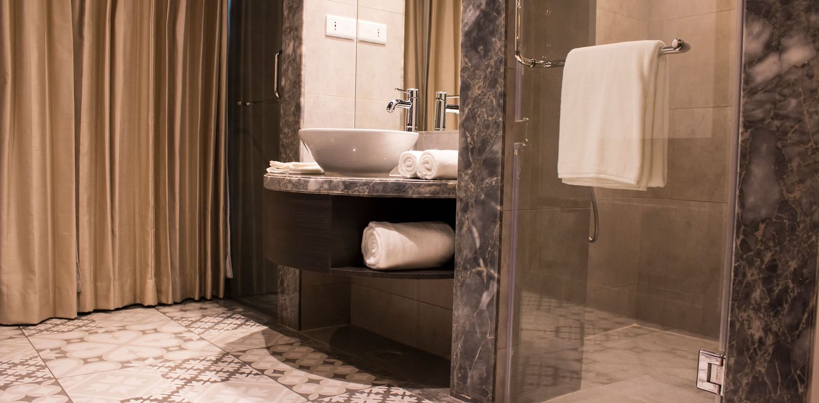 Wide view shot of a bathroom with a sink, mirrors  and towels | Regency Tirunelveli By GRT Hotels