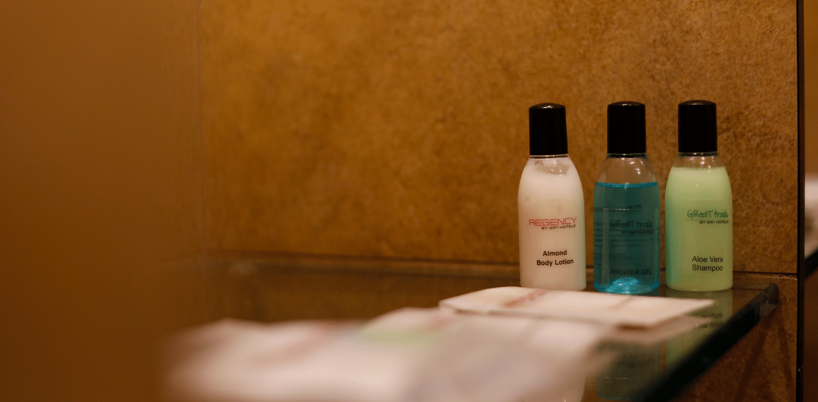 Image of various products in a bottle kept on the shelf with towel | Regency Tirunelveli By GRT Hotels