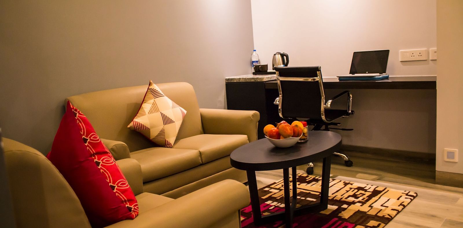 side view image of sofa and table kept inside a hotel room Image of a room with a bed and  pillows arranged on it  along with  a balcony | Regency Tirunelveli By GRT Hotels
