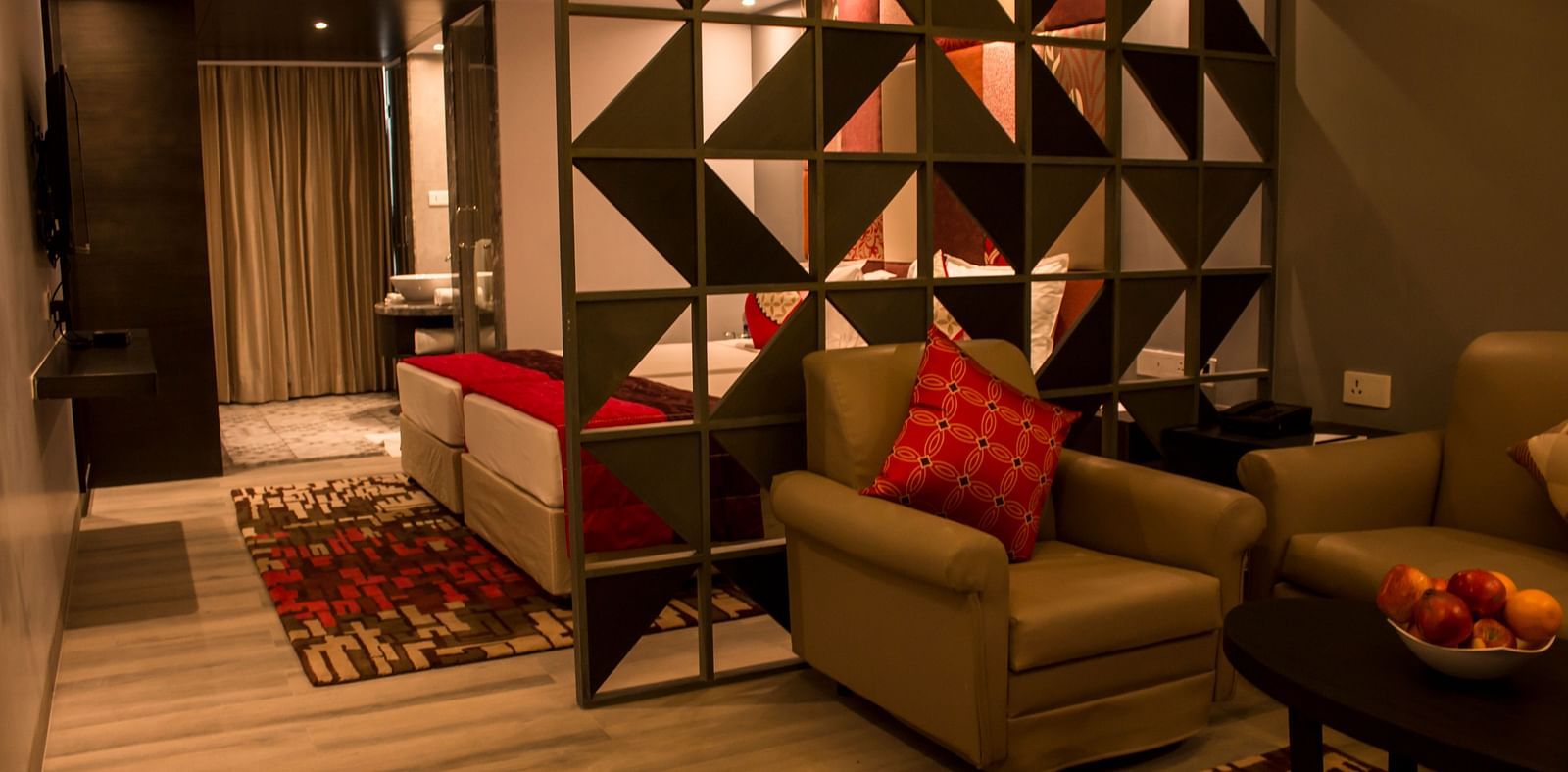 Full view image of sofa and table kept inside a hotel room Image of a room with a bed and  pillows arranged on it  along with  a balcony | Regency Tirunelveli By GRT Hotels