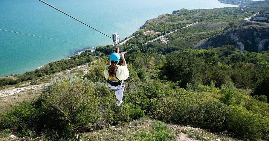 A woman on a zipline approaching the grassy land at the ground