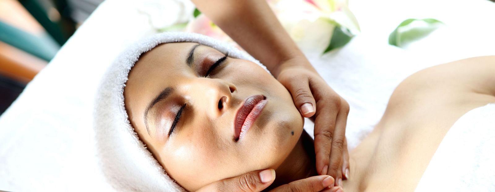 A woman laying on a spa table, receiving neck massage, exuding relaxation in a tranquil spa setting