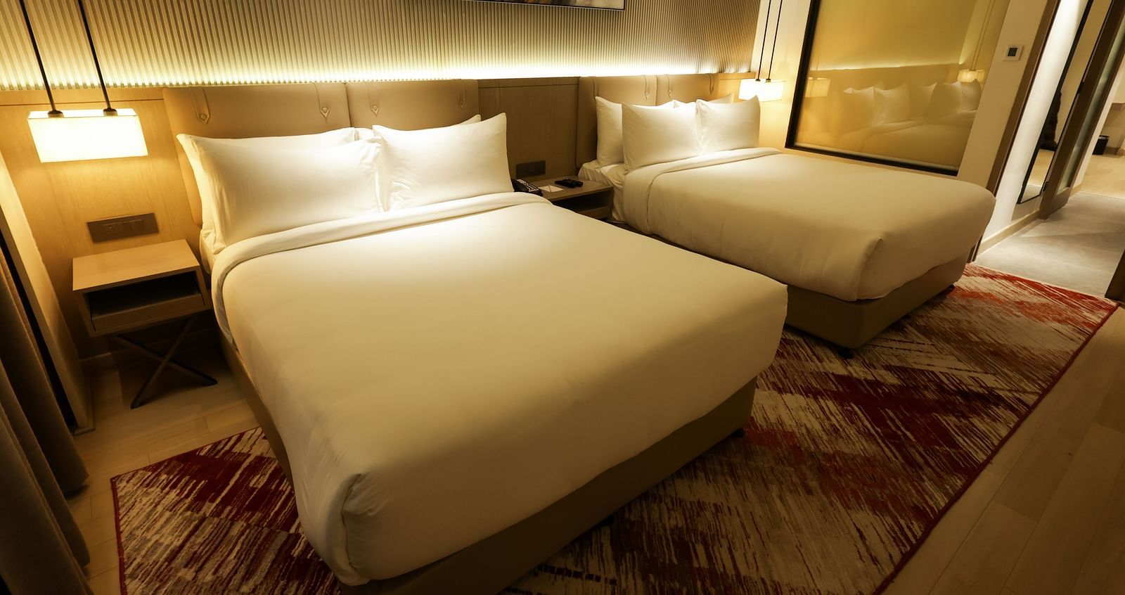Warmly lit bedroom with wooden furnishings and red-patterned carpet at Ramada by Wyndham Sonipat Murthal