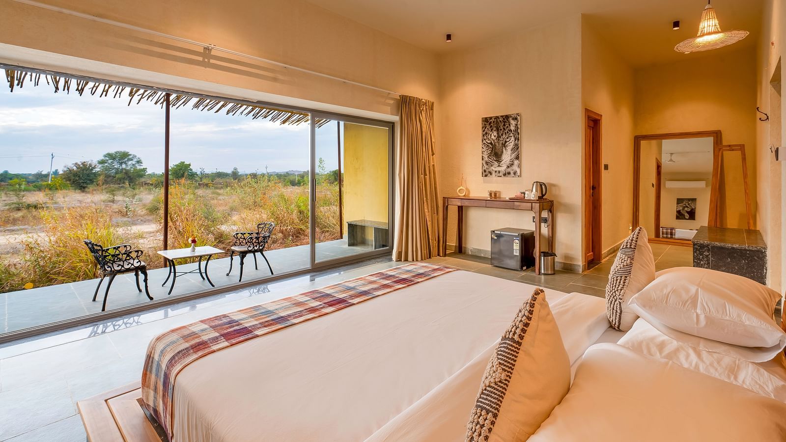An image of bedroom featuring a double size bed, a table with tea and coffee maker, and a courtyard with seating area at Kurja Jawai