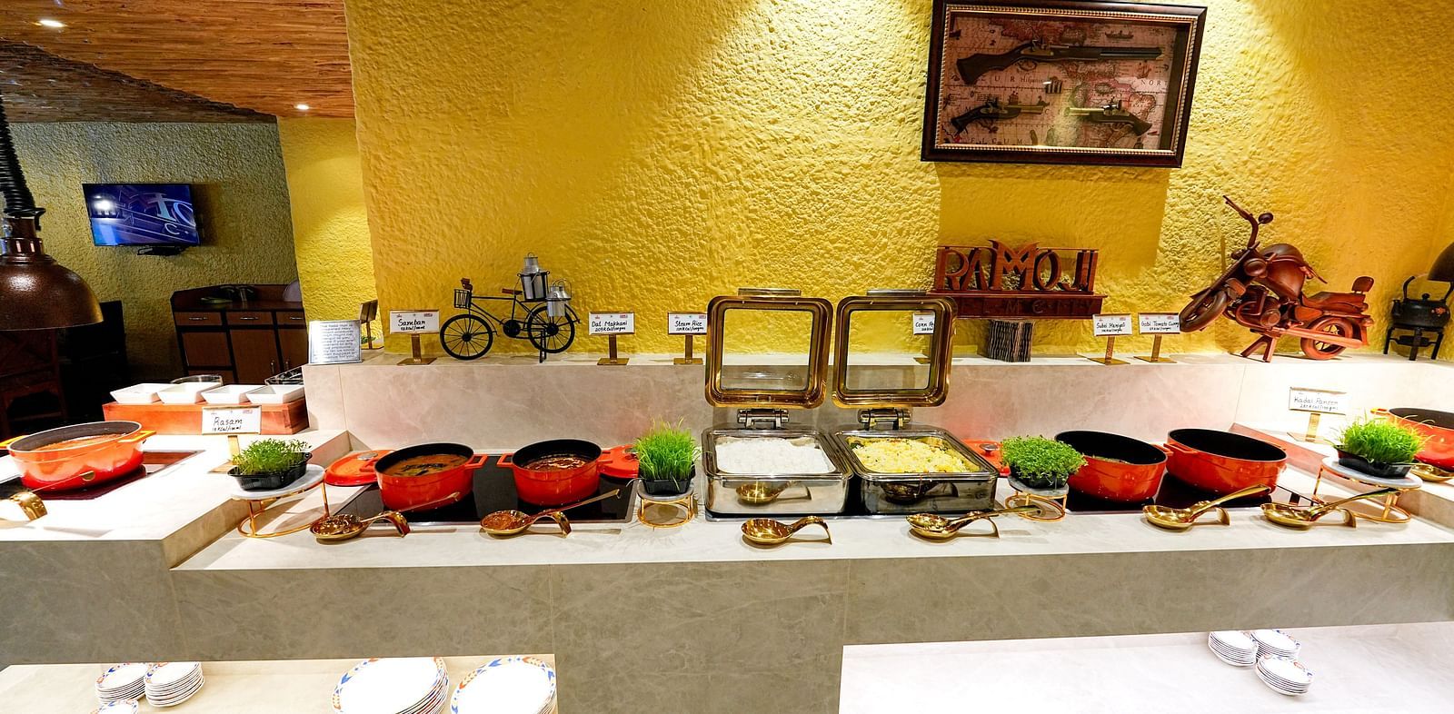 A buffet table showcasing colorful dishes and condiments under soft lighting at Tara, Comfort Hotel in Hyderabad - Ramoji Film City.