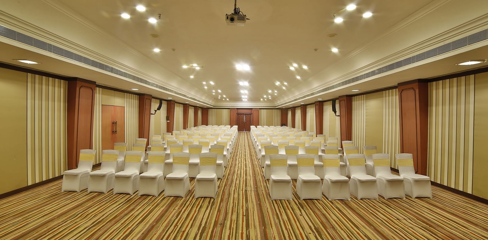  Seating arrangement in Terrace Hall A grand hotel suite with an opulent red and white decor, large bed, and seating area, reflecting a traditional style at Sitara Luxury Hotel in Hyderabad near Ramoji Film City.