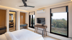 A spacious bedroom with large windows and a flat-screen TV at The Sierra
