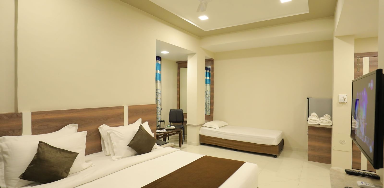 Close up of the king size bed and single bed in the Suite of Highland Resort, facing a wall-mounted TV.