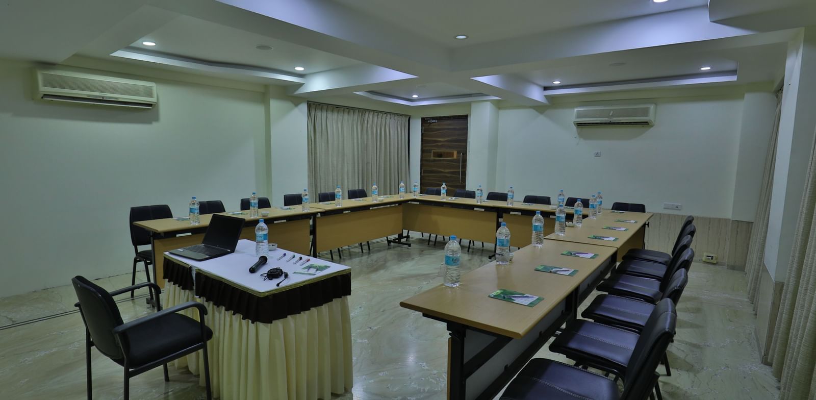 A formal meeting room with a large U-shaped table, office chairs, and a podium at the front - Retreat Heritage, Lonavala