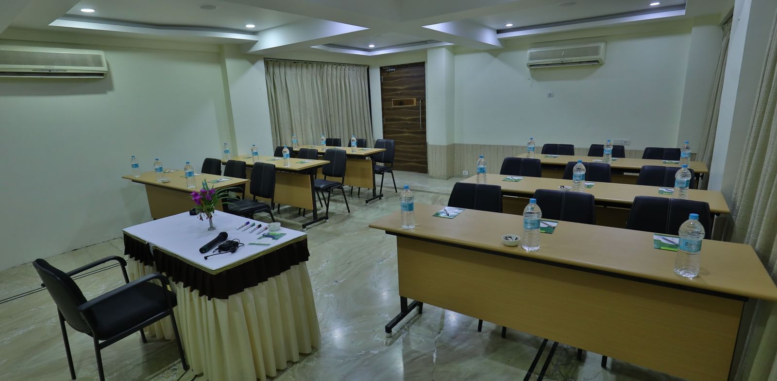 A conference room featuring multiple tables arranged individually, chairs, and a podium at the front - Retreat Heritage, Lonavala